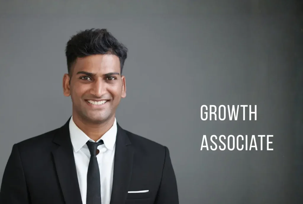 Smiling man in a black suit and tie with "Growth Associate" text overlay against a grey background.