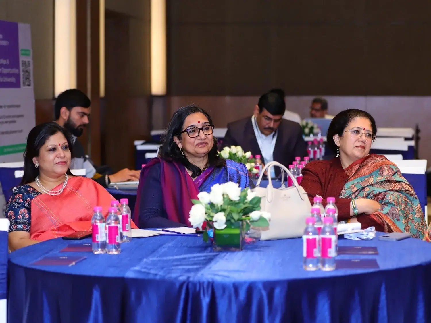 Three women in sarees and professional attire seated at a blue table during a Career Plan B educational conference.