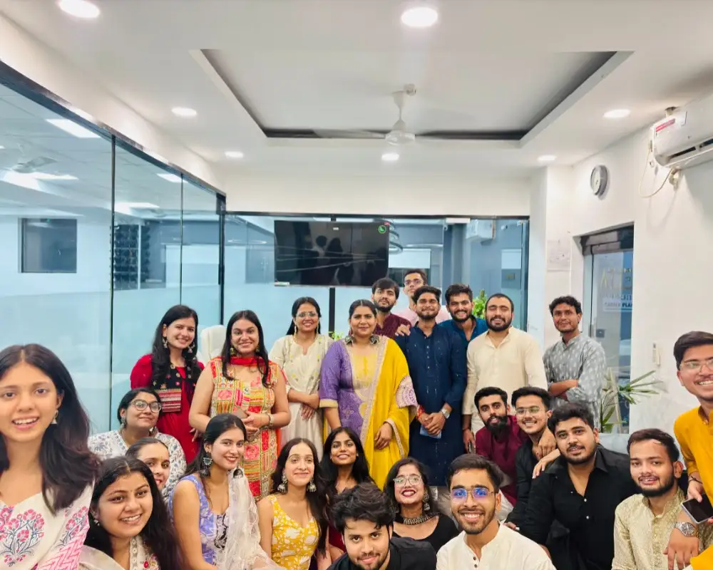 Team meetingCareer Plan B team in ethnic wear posing for a group photo in a modern office with glass partitions.