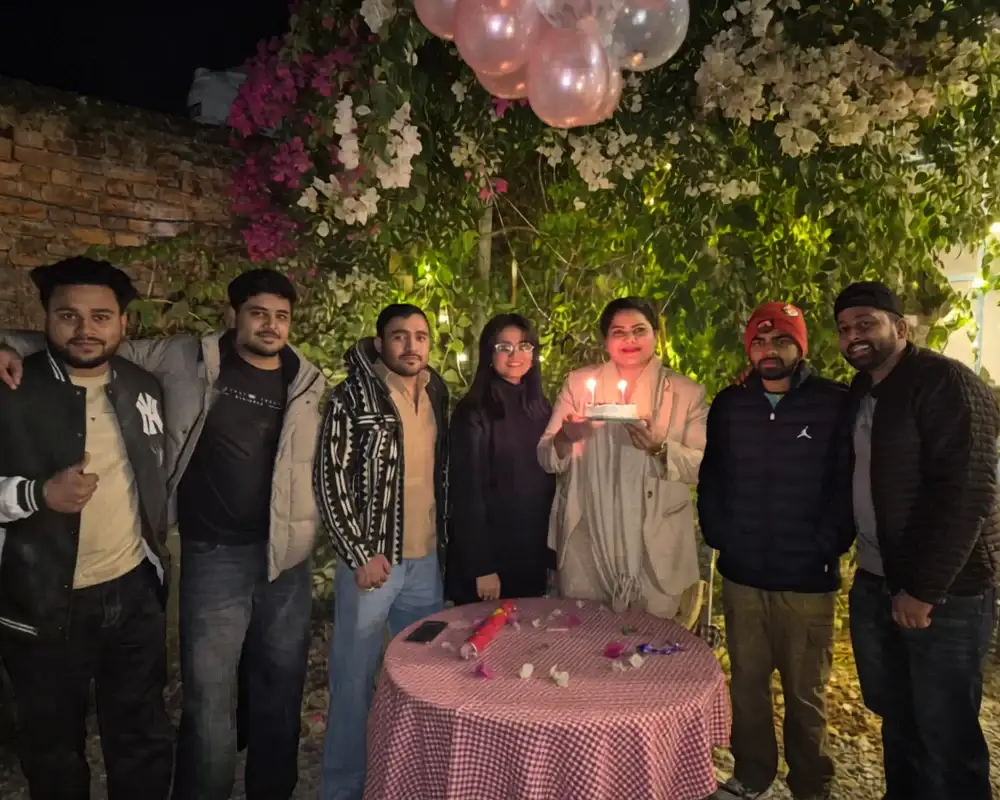Career Plan B founder holding a birthday cake with lit candles surrounded by team members at an outdoor evening celebration.
