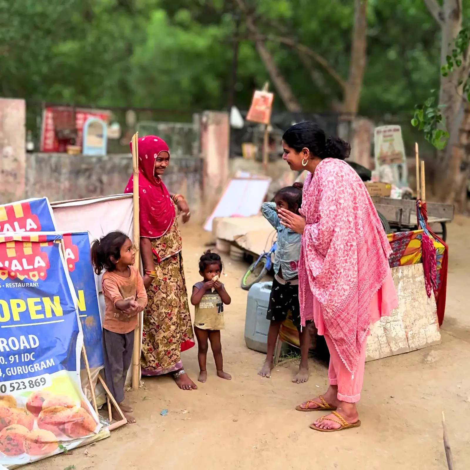 Career Plan B founder Shahnaz Hussain in pink greeting a woman and children at a community site in Gurugram.