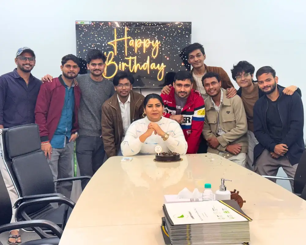 Career Plan B team celebrating a birthday with a chocolate cake in a conference room with a Happy Birthday digital screen.