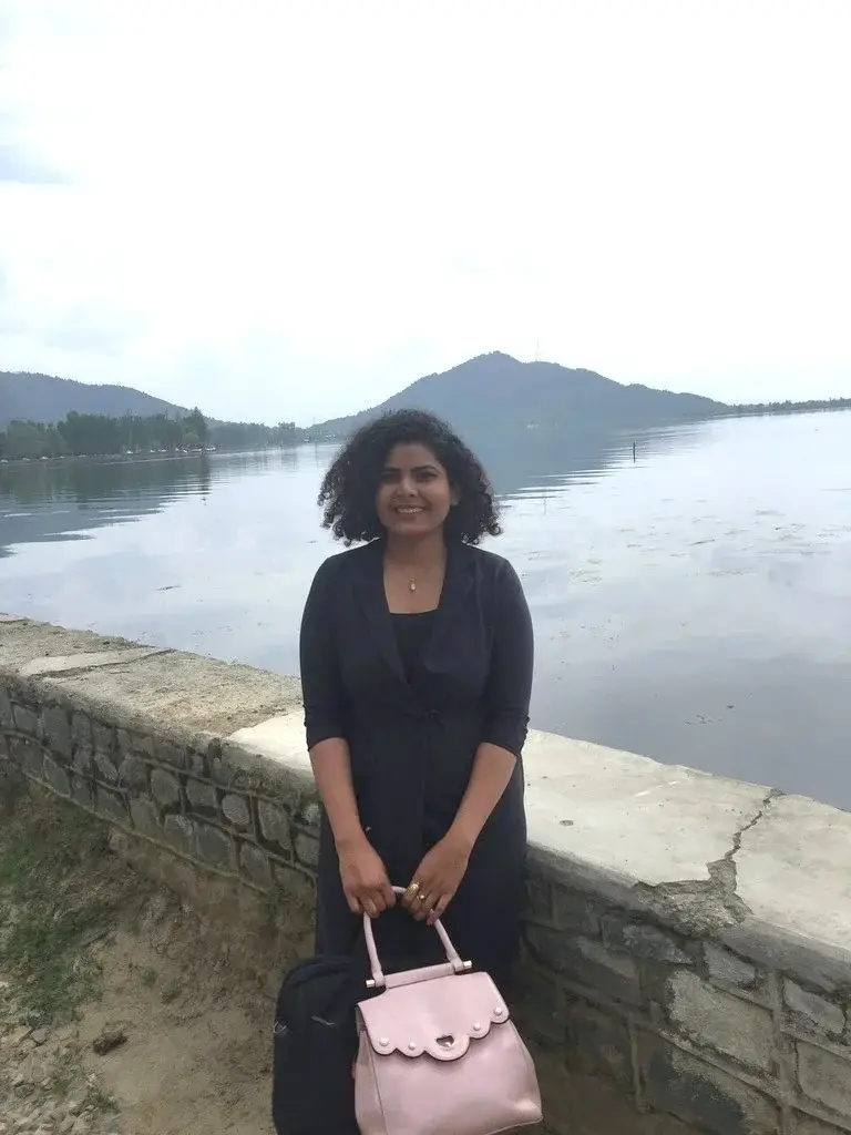 http://Career%20Plan%20B%20founder%20Shahnaz%20Hussain%20in%20a%20black%20dress%20standing%20by%20a%20stone%20wall%20with%20a%20calm%20lake%20and%20mountains%20behind%20her.