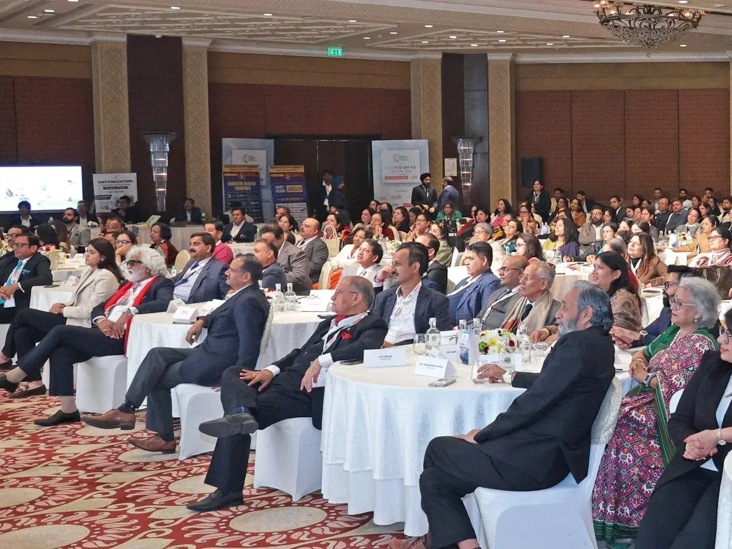 Audience attending a career guidance event in a large, crowded seminar hall with round table seating.